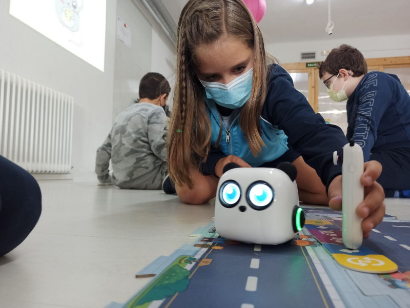 Una niña manejando y programando un robot